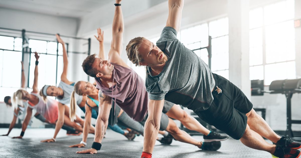 Group of people performing side plank exercises in a gym.