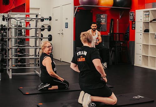 People performing exercises on yoga mats in a gym