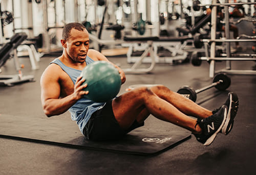 Person performing sit-ups with a medicine ball in the gym