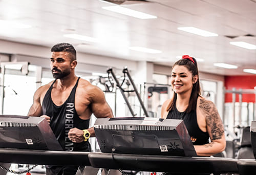 Two people running on treadmills in the gym